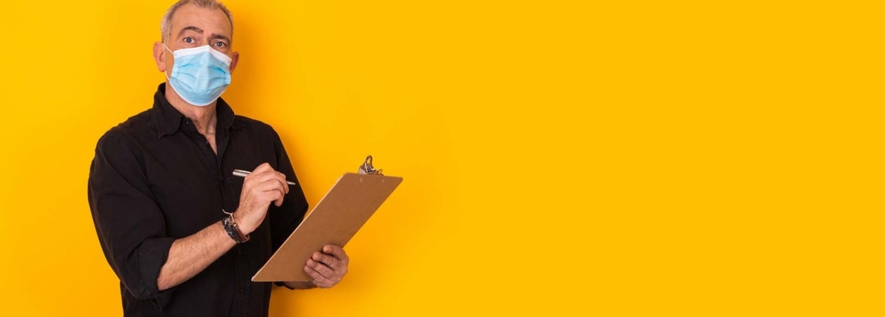 Medewerker met mondkapje heeft een pen met schrijfblok in de hand