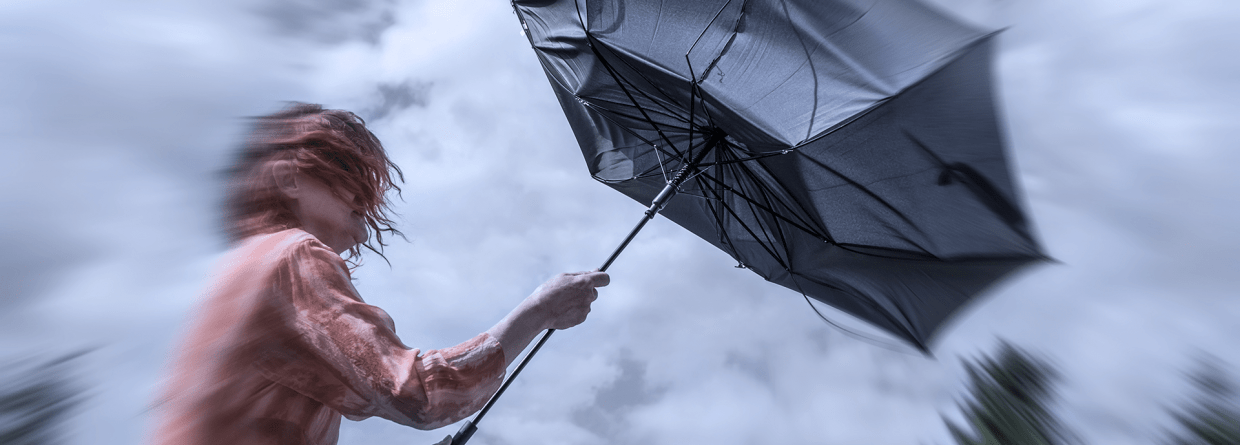 Vrouw met rood haar houdt een paraplu vast in de storm